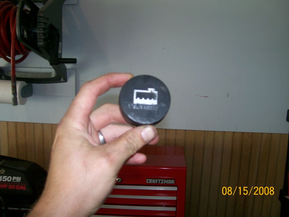 Radiator cap with coolant level warning symbol held in hand