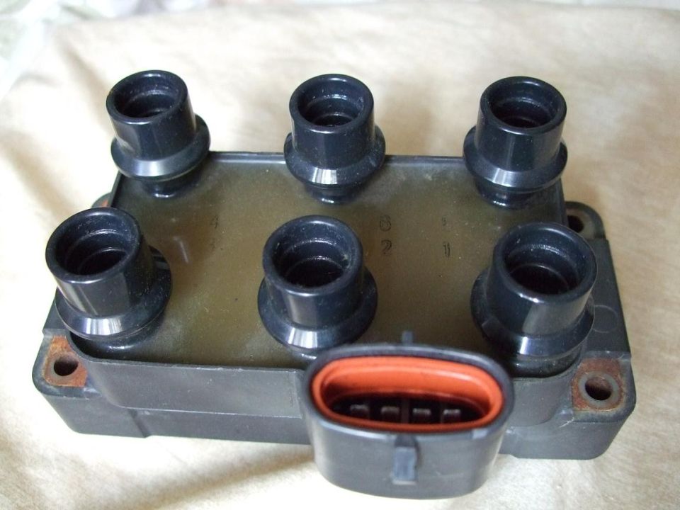Ignition coil pack with six black spark plug boots and an orange-trimmed connector