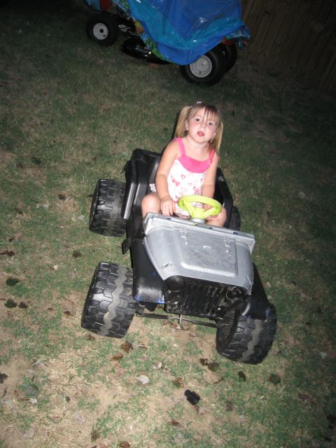 1994 Ford Bronco - A young girl sits in a toy Jeep with oversized tires, with another covered ride-on toy in the background.
