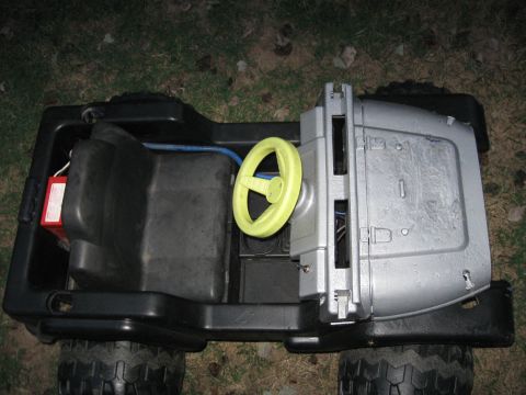 1994 Ford Bronco - Interior view of a black plastic toy ride-on vehicle with a yellow steering wheel and gray dashboard.