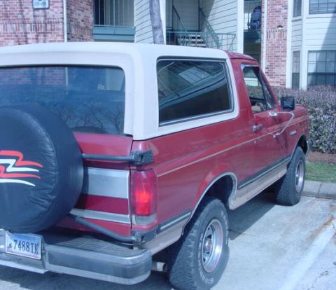 1987 Ford Bronco - Rear view of a red 1987 Ford Bronco parked outside an apartment building.