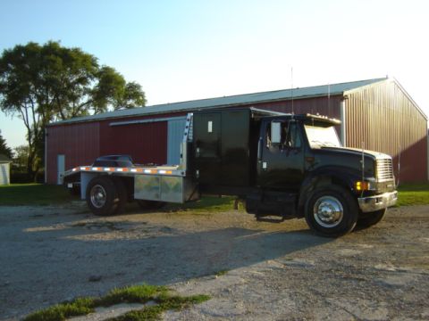 1992 Ford Bronco - This black flatbed truck features a custom sleeper cab and is parked in front of a large red barn.