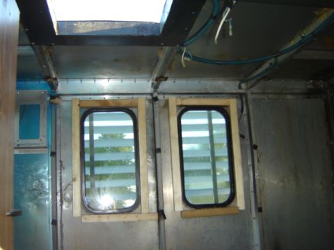 1992 Ford Bronco - The interior of a vehicle shows unfinished construction with metal walls and two windows.