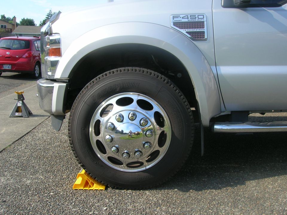 Front wheel and fender of a silver 2008 Ford F-450 Super Duty truck, parked on yellow wheel chocks