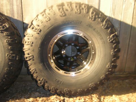 1996 Ford Bronco - A Super Swamper tire mounted on an ION Alloy rim is shown against a wooden background.
