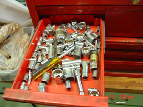 1985 Ford Bronco - A red toolbox drawer is open, revealing a collection of various sockets and wrenches, along with a yellow-handled screwdriver.