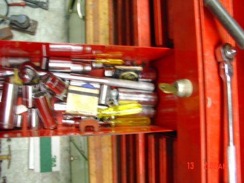 1985 Ford Bronco - Contents of a red toolbox drawer, including various hand tools and a key in the lock.