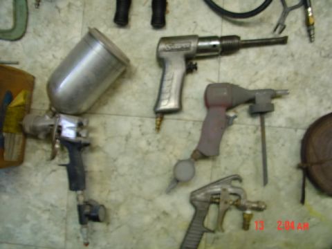 1985 Ford Bronco - A collection of pneumatic tools, including a spray gun and a hammer, are arranged on a tiled surface.