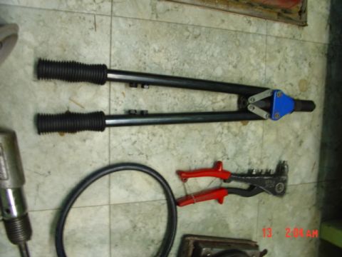1985 Ford Bronco - Various tools, including a rivet gun and a hose, are laid out on a tiled surface.