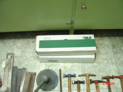 1985 Ford Bronco - Assorted body hammers and 3M sandpaper boxes are laid out on a tiled floor.