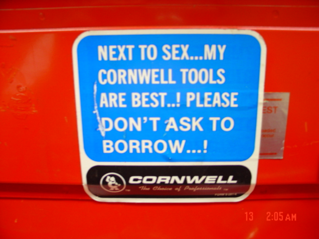 Blue and white sticker with text about Cornwell tools on a red surface