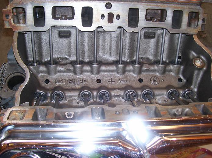 Ford 351W engine lifter valley with pushrods installed, intake removed, chrome valve cover below