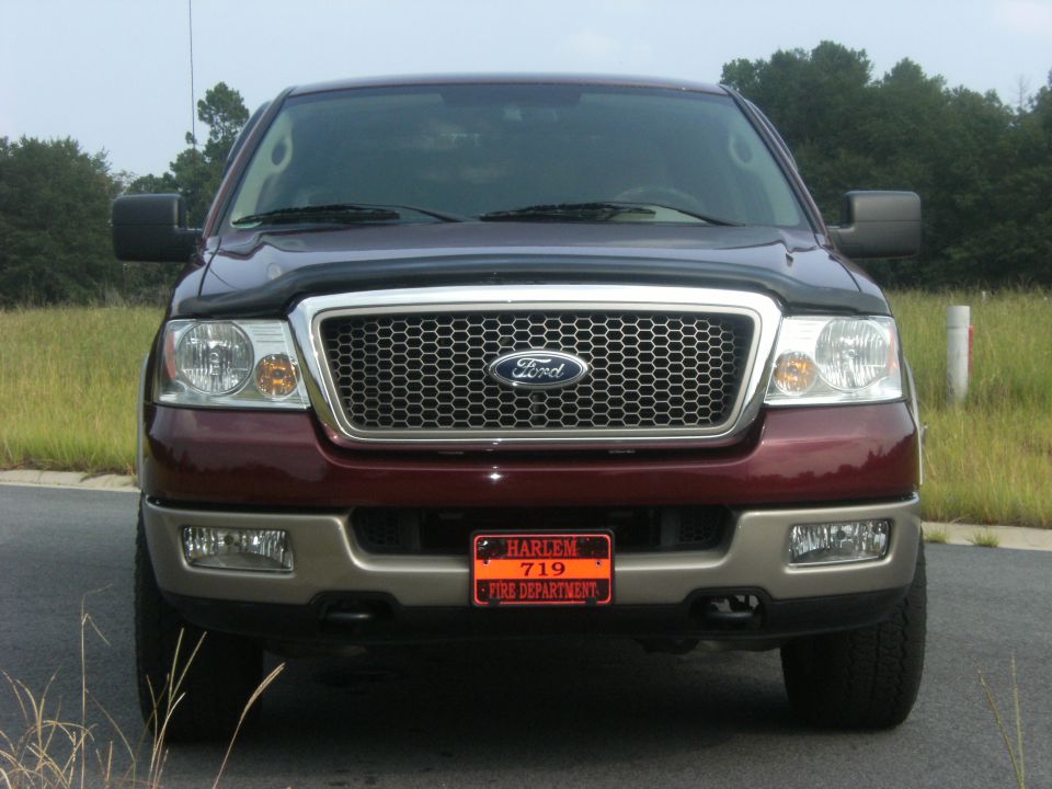 Front view of a maroon Ford F-150 truck with a chrome grille and a Harlem Fire Department license plate