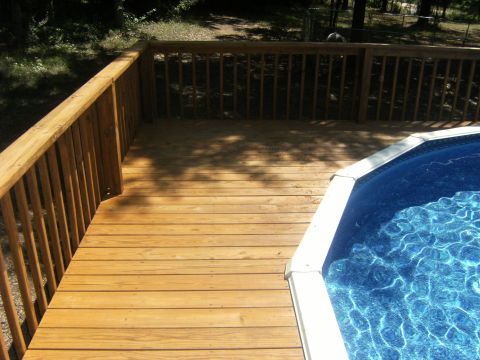 1992 Ford F-150 - A wooden deck surrounds a portion of an above-ground swimming pool on a sunny day.