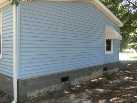 1992 Ford F-150 - Side view of a house showing light blue siding and a concrete block foundation.