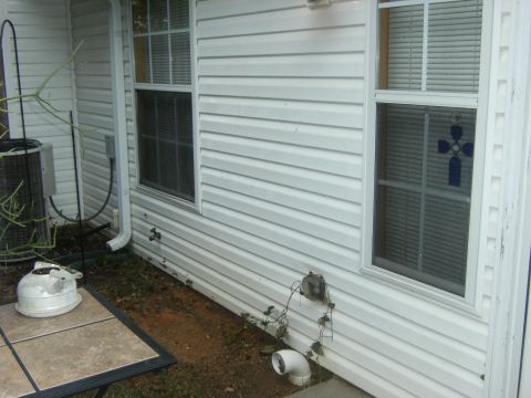 1992 Ford F-150 - The exterior of a house is shown with white vinyl siding and two windows. An air conditioning unit is visible on the left.
