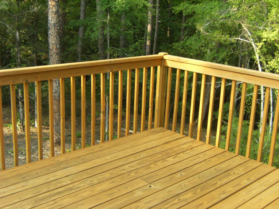 Wooden deck railing and floor with trees in the background. Supermotors logo in the corner