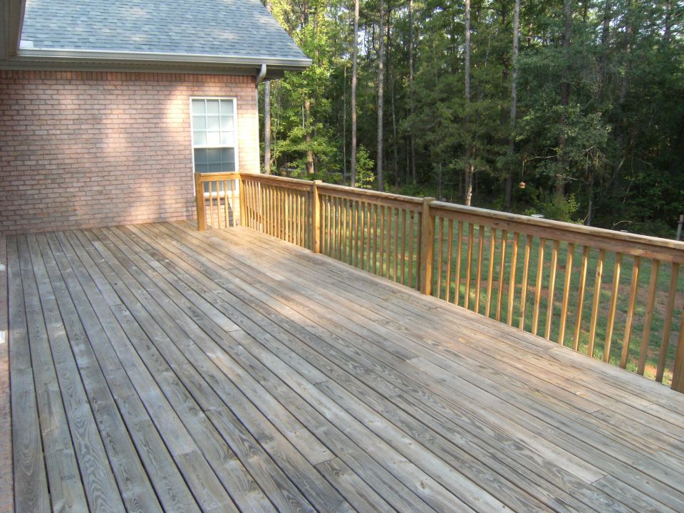 Wooden deck with a brick house and trees in the background