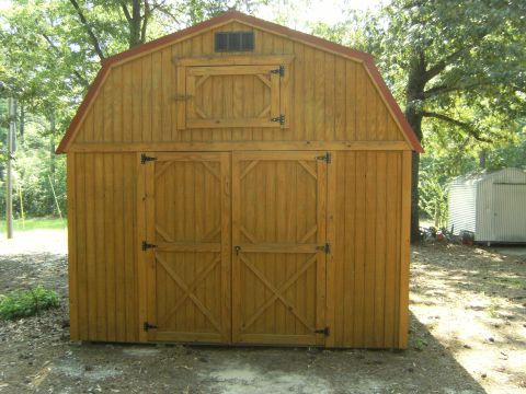 1992 Ford F-150 - A wooden storage building with a red roof and double doors sits outdoors among trees.