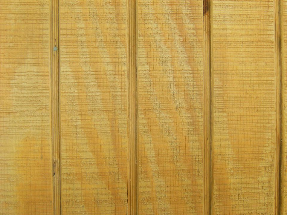 Close-up of rough-sawn stained vertical wood plank siding grain