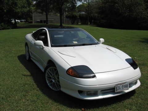 1992 Dodge Stealth - This Mitsubishi 3000GT features pop-up headlights and a black roof, parked on a grassy lawn.