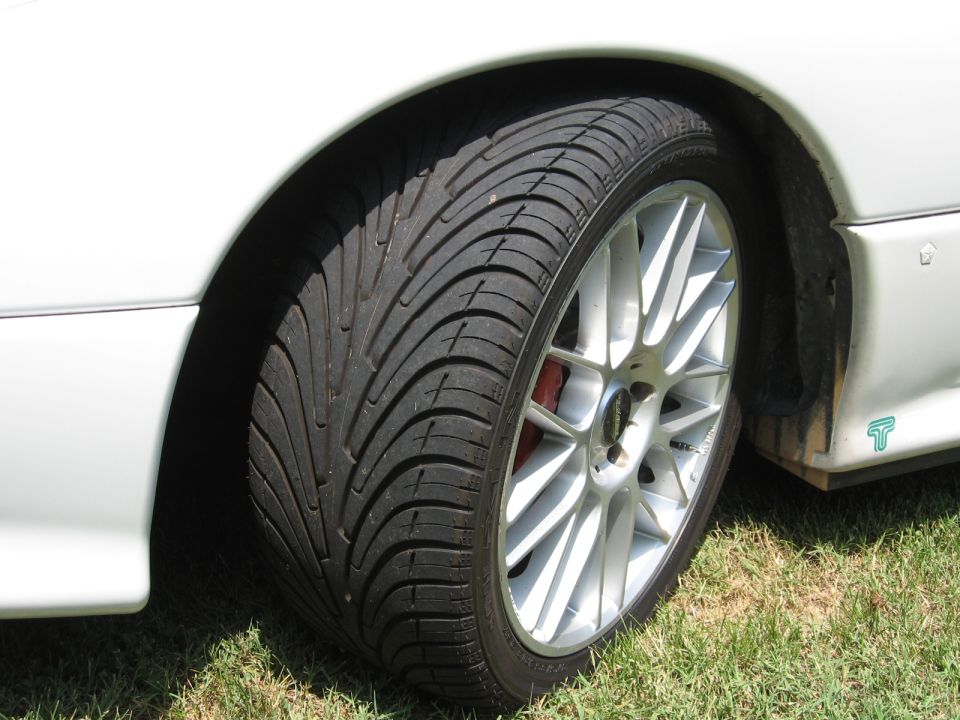 Close-up of a white car's front wheel and fender with a silver multi-spoke rim