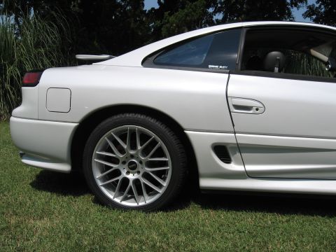 1992 Dodge Stealth - Side view of a white sports car with aftermarket wheels parked on grass.