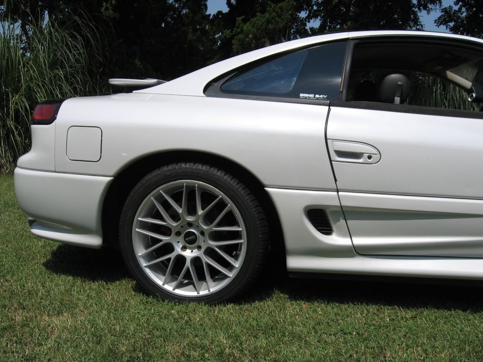 Rear quarter of a white Dodge Stealth on grass with silver mesh alloy wheel and red caliper