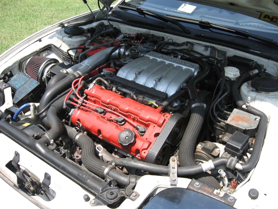 White car engine bay with red valve covers and silver intake manifold