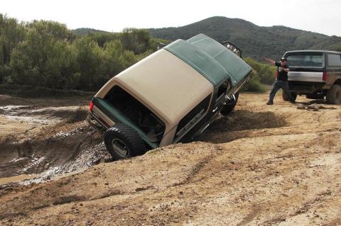 1991 Ford Bronco - Two Ford Broncos navigating a challenging off-road course with one vehicle stuck in the mud.