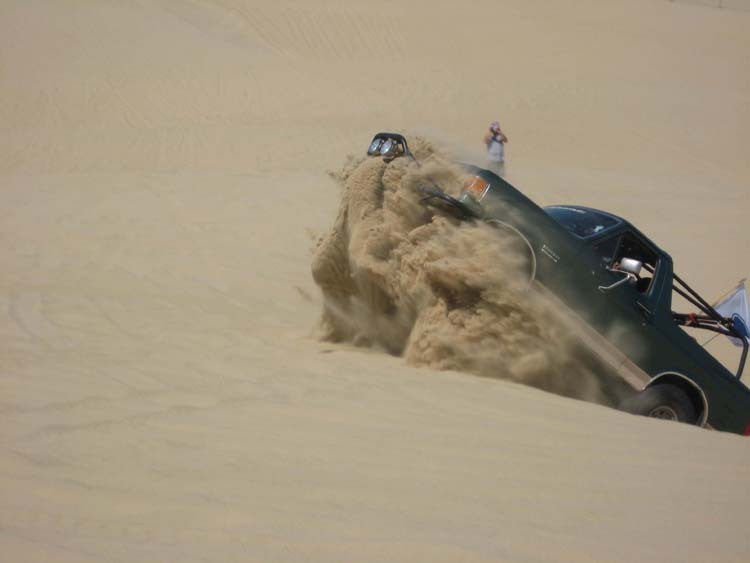 Dark green 1991 Ford Bronco kicking up sand