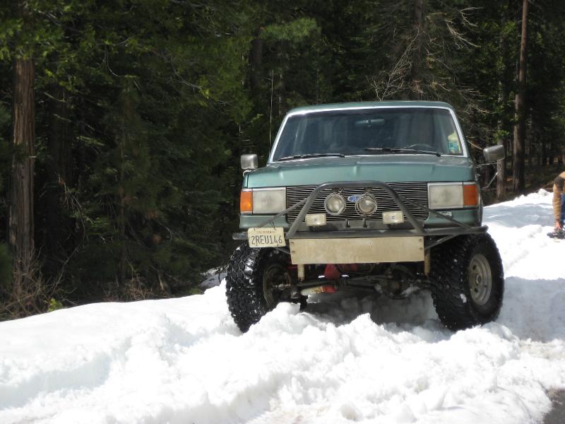 1991 Ford Bronco with custom bumper and lights driving in snow