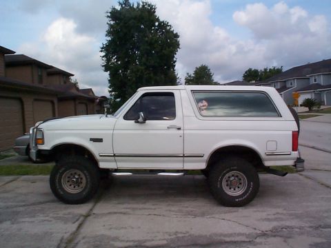 1992 Ford Bronco - Side profile of a white 1992 Ford Bronco parked in front of a residential building.