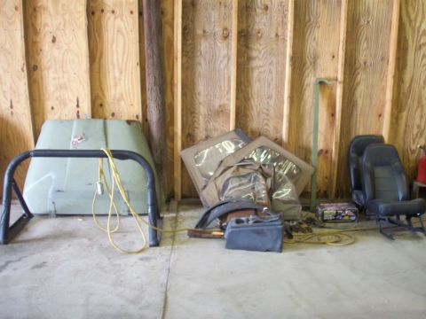 1978 Jeep CJ5 - Stored Jeep CJ5 parts including hood, soft top, and seats against a plywood wall.
