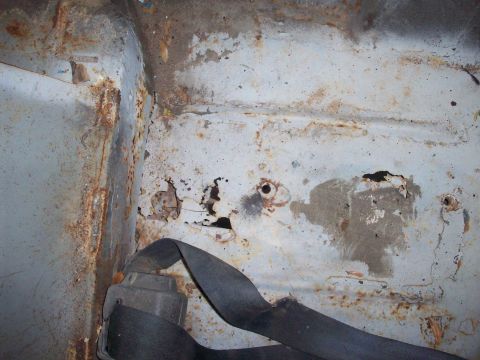 1978 Jeep CJ5 - The interior of the vehicle shows extensive rust damage and a seatbelt mechanism.