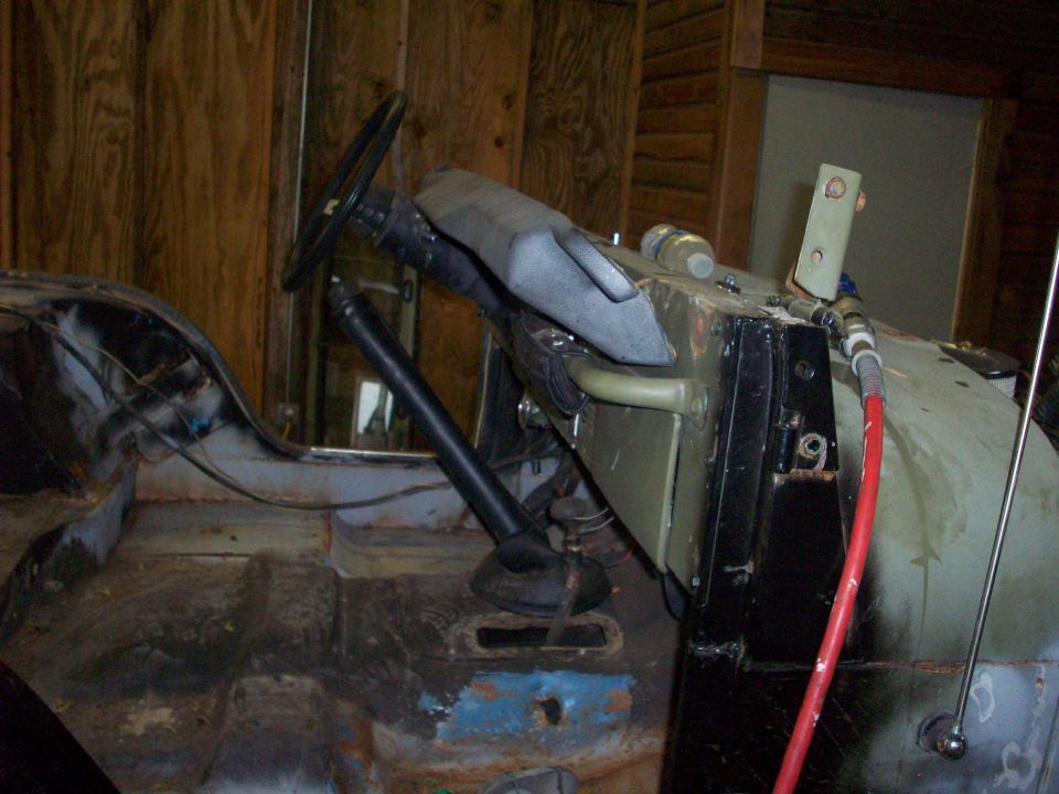 Jeep interior with steering wheel, dashboard, and floor showing rust and some blue paint