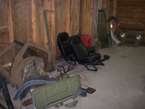 1978 Jeep CJ5 - Various Jeep CJ5 parts are organized in a garage, including a tailgate, grille, and seats.
