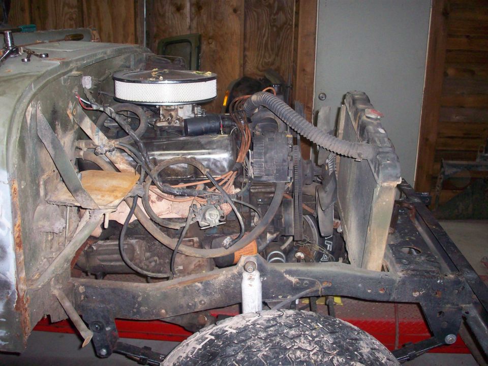 Jeep CJ5 engine bay with V8 engine, air cleaner, radiator, and suspension components visible