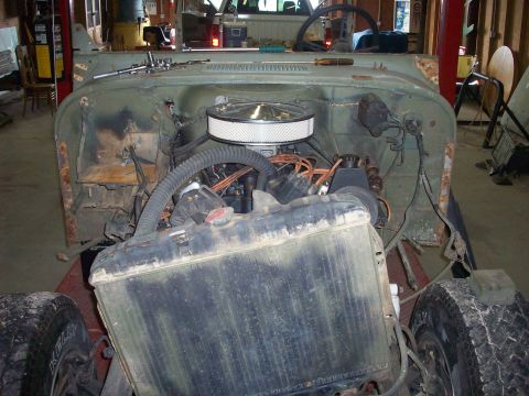 1978 Jeep CJ5 - The engine bay of a Jeep is shown with the hood removed, revealing the engine and radiator.