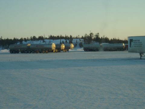 1995 Mercury Grand Marquis - Tanker trucks are parked in a snowy field under a clear sky. A Norstar trailer is visible on the right side of the image.