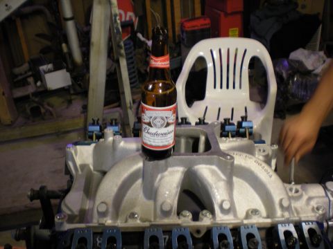 1985 Ford Bronco - An engine intake manifold is shown with a beer bottle resting on it, in a cluttered garage setting.