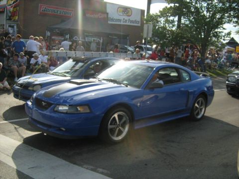 1988 Mercury Grand Marquis - A blue Ford Mustang is on display at a car event, with spectators gathered around.