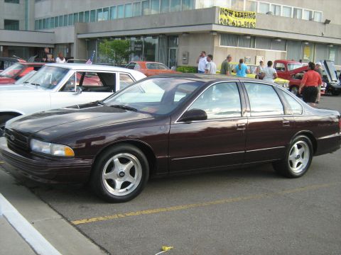 1988 Mercury Grand Marquis - A row of cars are parked in front of a building with a 'Now Leasing' sign.