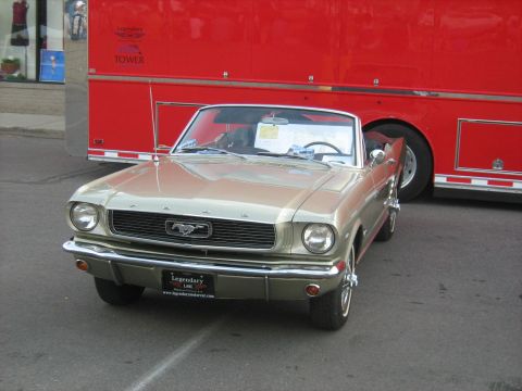 1988 Mercury Grand Marquis - A classic Ford Mustang convertible is seen parked next to a large red trailer at an outdoor event.