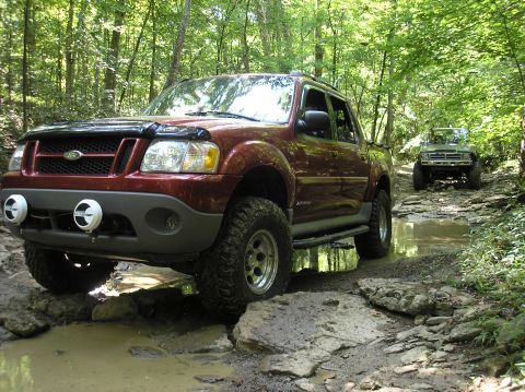 2002 Ford Sport Trac - A maroon Ford Sport Trac drives through a muddy, rocky trail with another vehicle following behind in the woods.