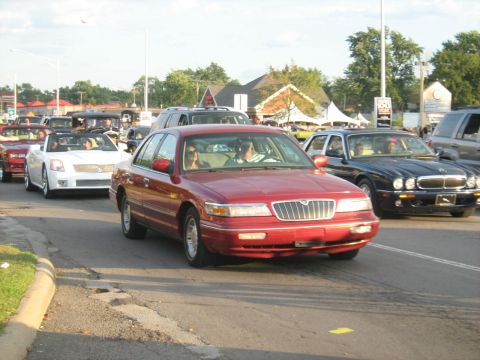 1988 Mercury Grand Marquis - A red sedan is seen in a line of cars on a sunny day.