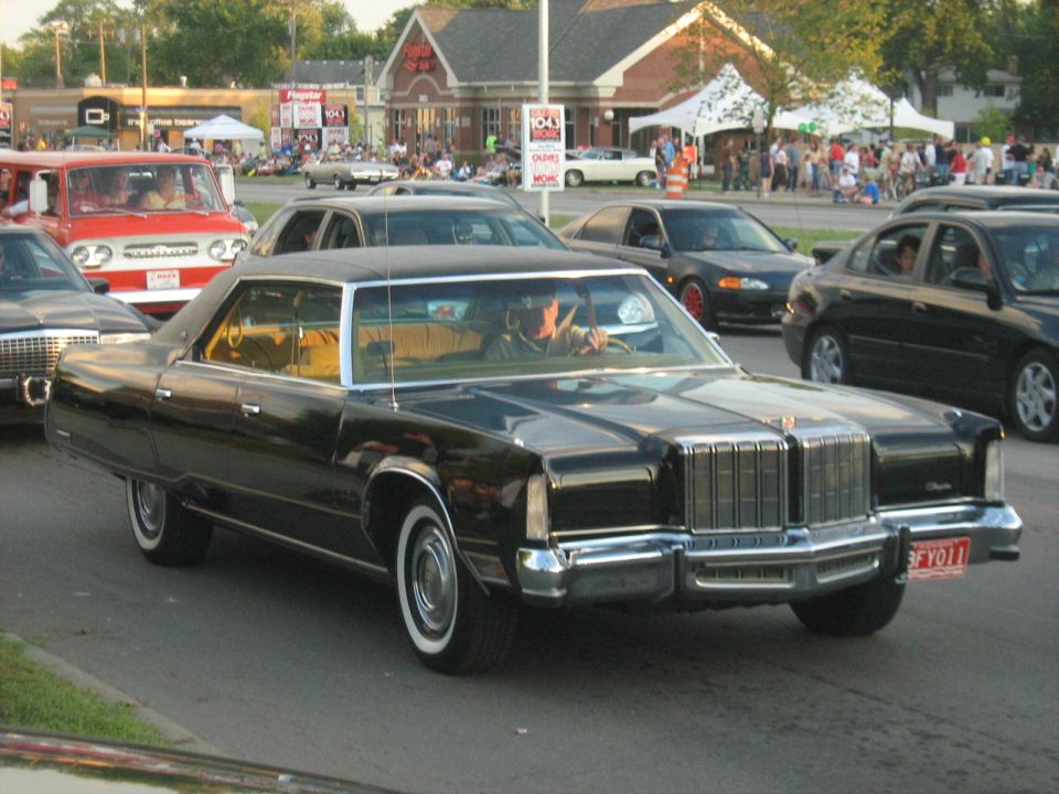Black 1970s sedan with prominent chrome grille and whitewall tires