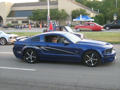 1988 Mercury Grand Marquis - A blue Ford Mustang GT with racing stripes is seen driving in a parade.