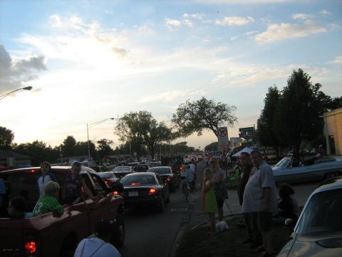 1988 Mercury Grand Marquis - A crowded street scene with many cars and onlookers, possibly during a parade or event.