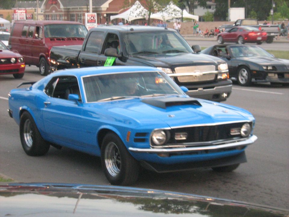 Blue 1970 Ford Mustang fastback with a hood scoop, chrome bumper, and black wheels
